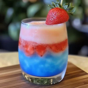 Patron Strawberry Blue Hawaiian – a colorful layered drink with bright blue, red, and white frozen layers, garnished with a fresh strawberry.