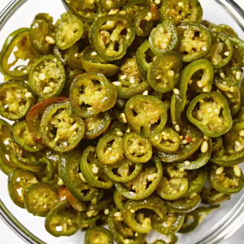 Bowl filled with homemade cowboy candy—sweet and spicy candied jalapeño slices.