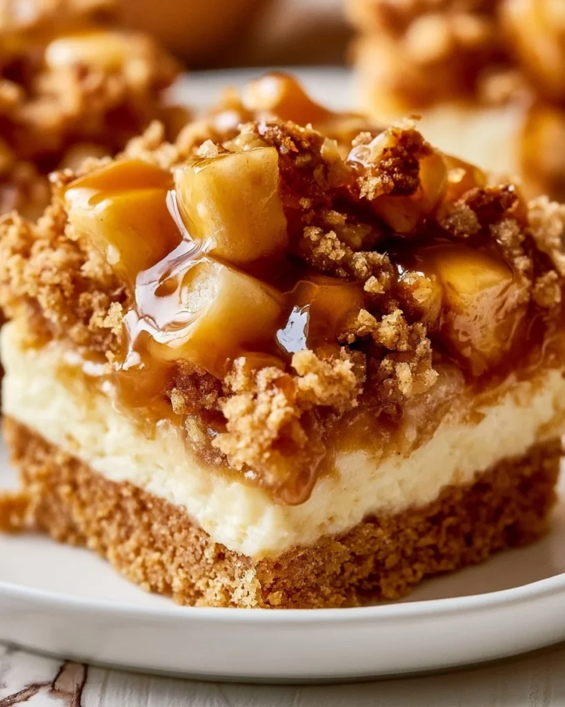 Creamy caramel apple cheesecake bars topped with caramel sauce and apple slices.